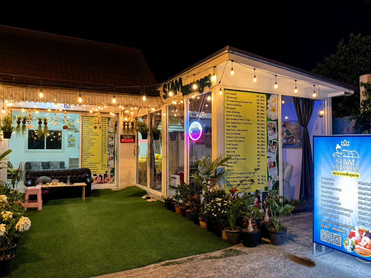 The front of the salon at night, with the treatment board lit in the window, the garden of potted plants and the reception room behind.