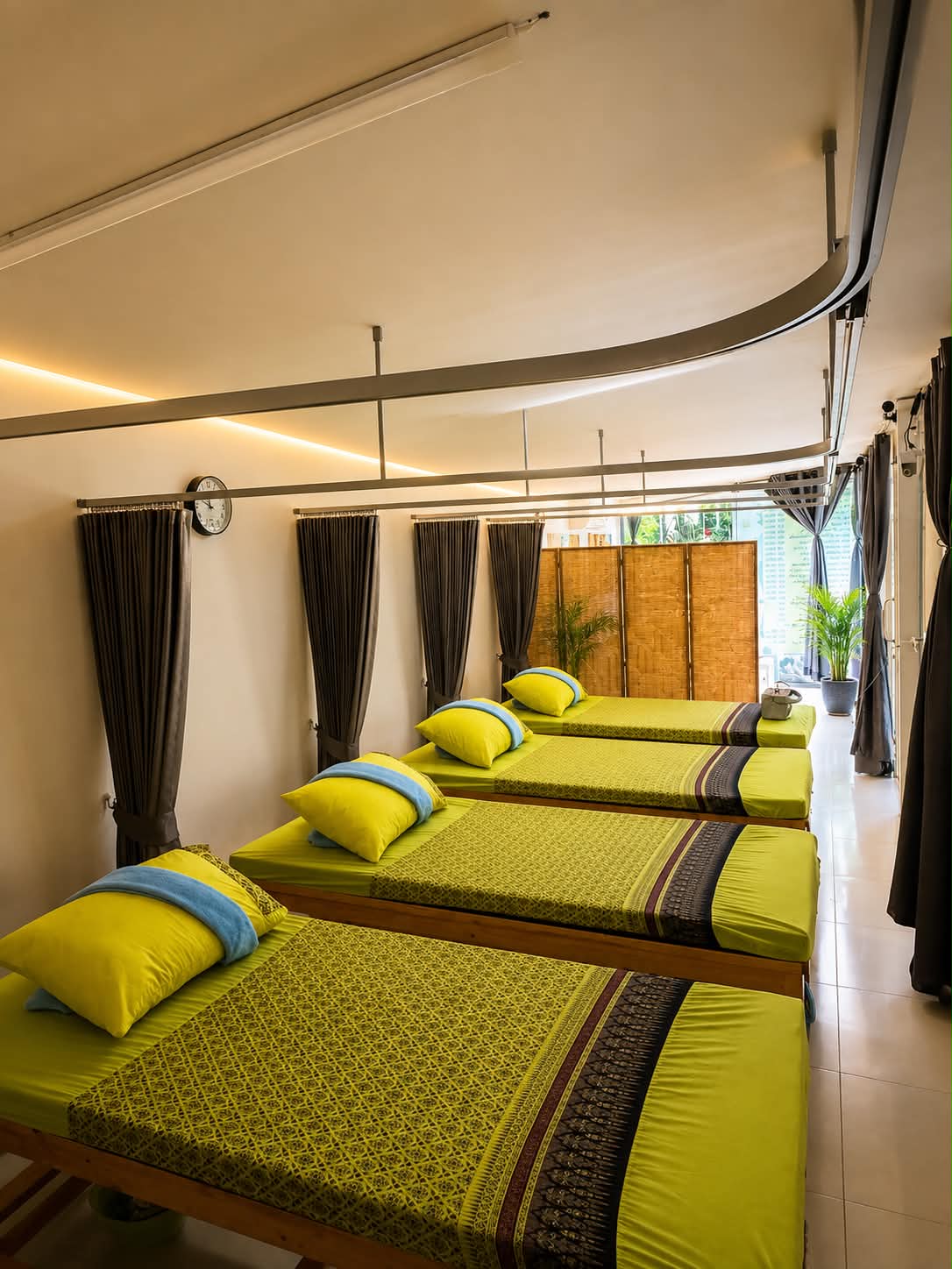 The Thai massage room: low mattresses dressed in lime green with woven Thai runners, along a curtained wall.