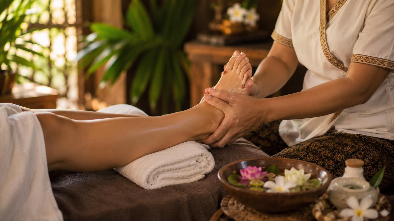 A foot massage in progress, a bowl of flowers set beside the couch.